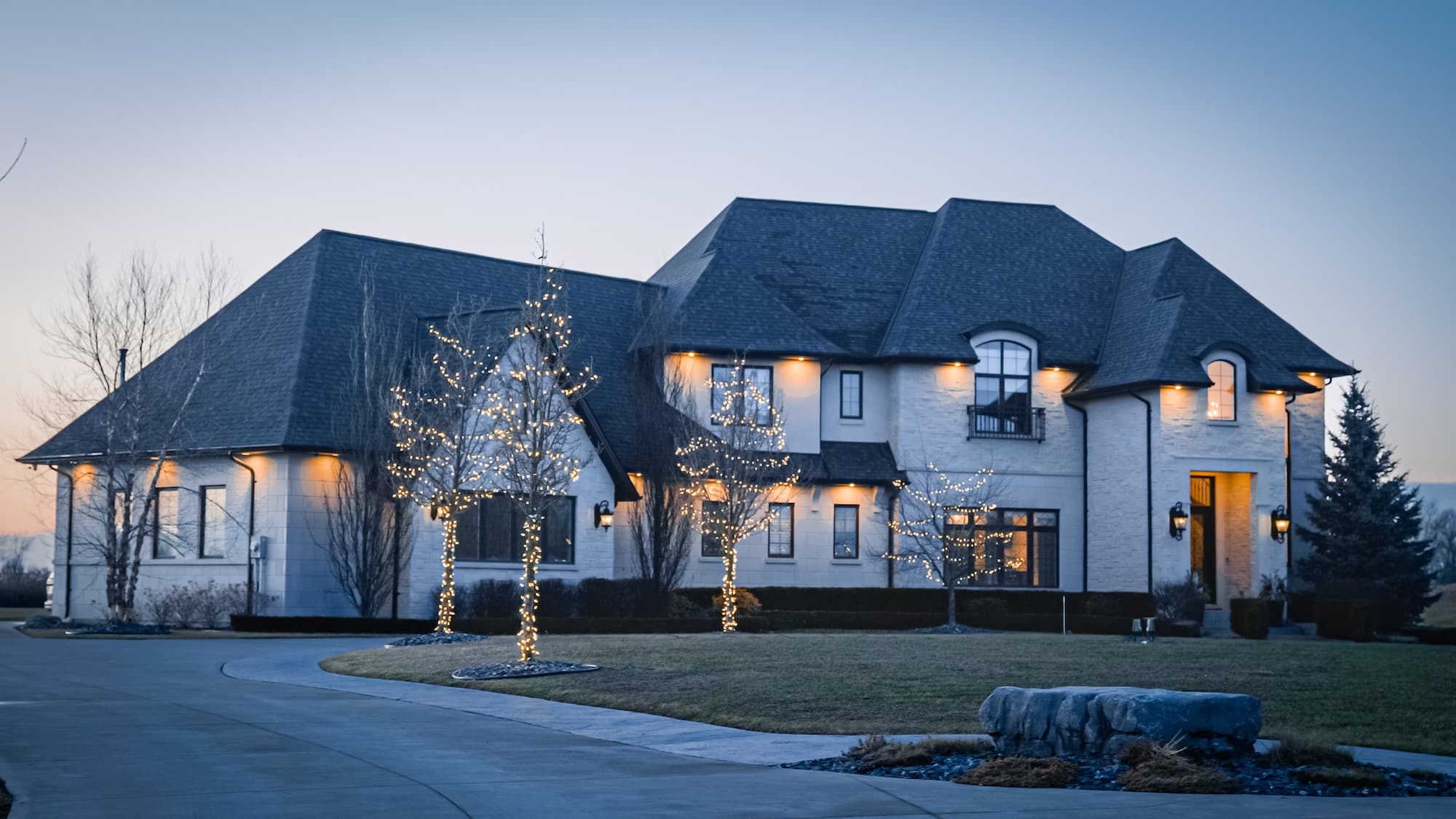 White brick custom estate home at twilight by Timberland Homes in LaSalle, Ontario.