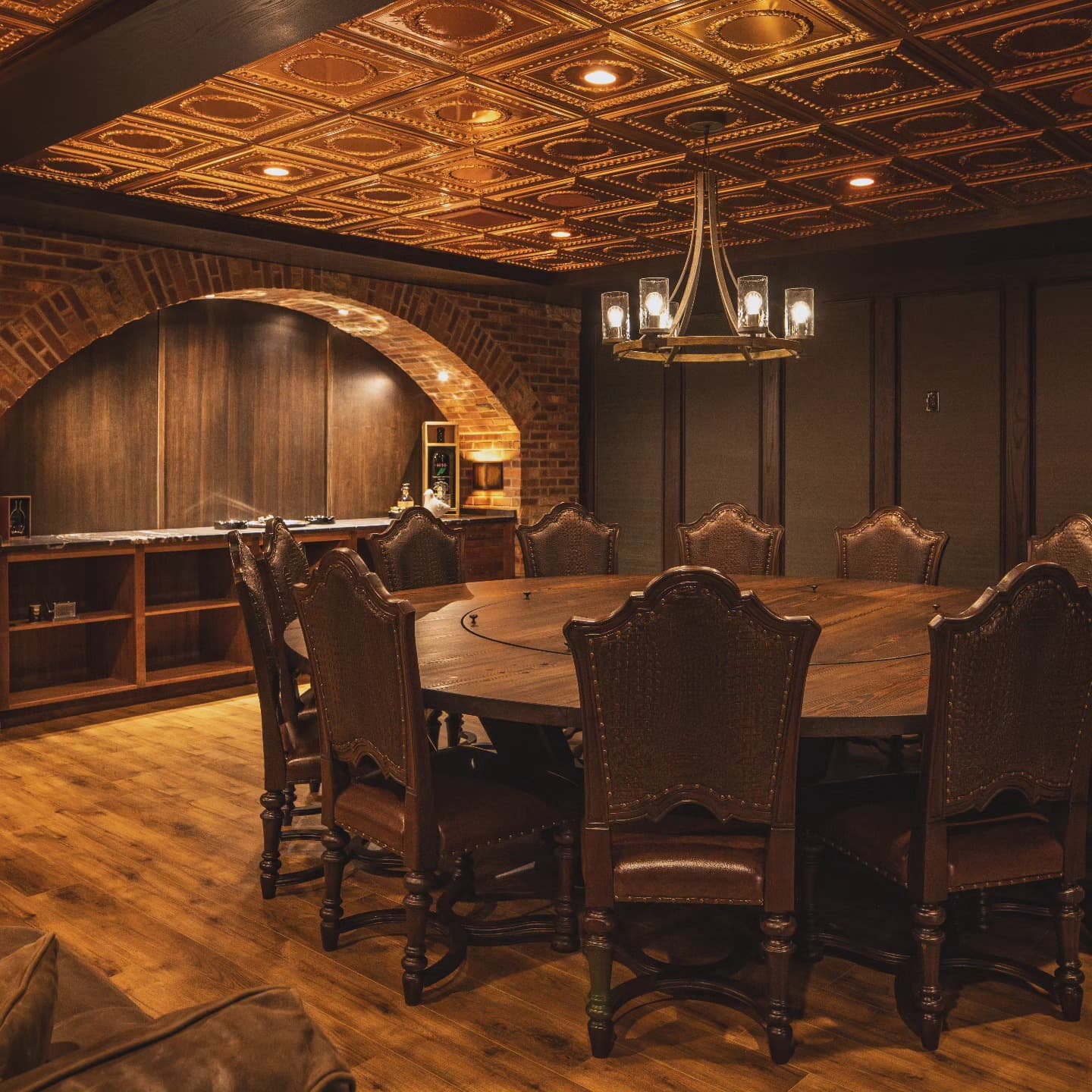 Custom speakeasy-style lounge with ornate tin ceiling, brick arches, and leather seating in a Timberland home in Chatham, Ontario