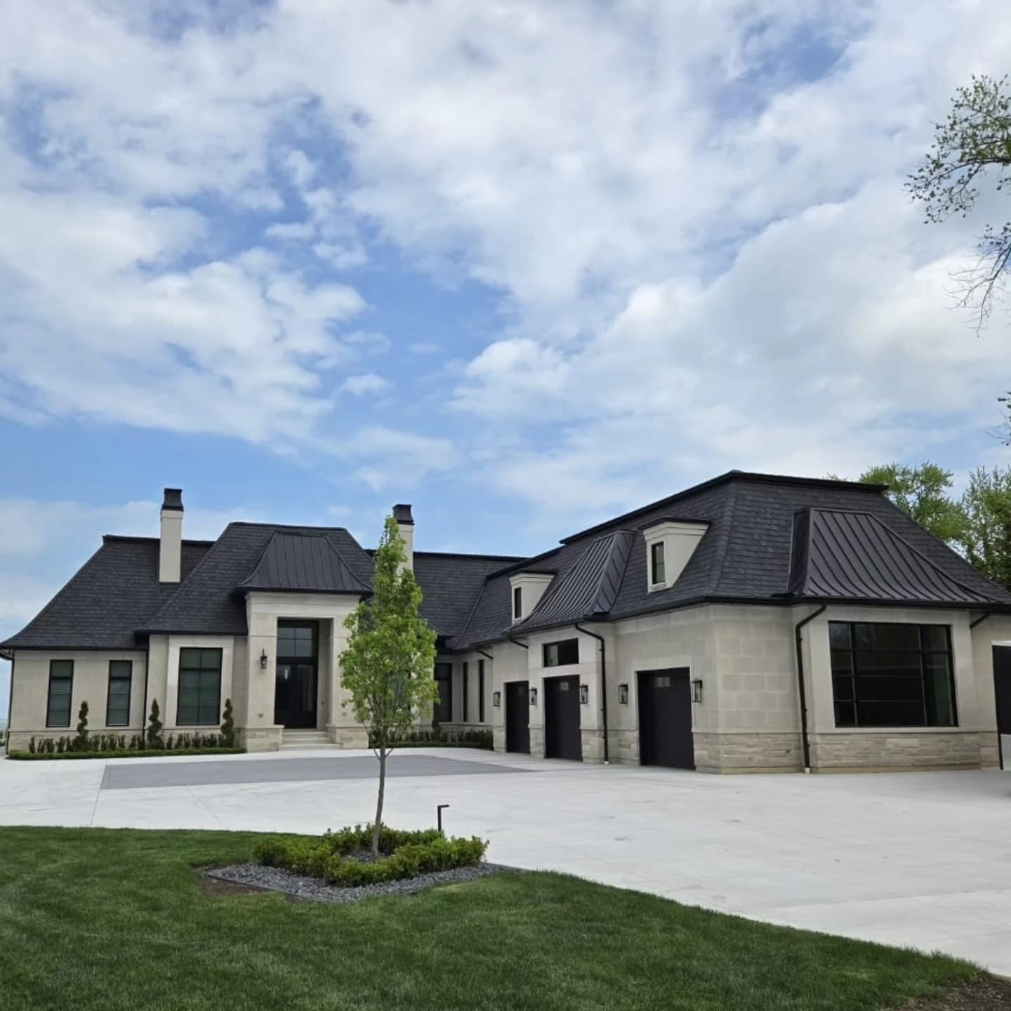 Grand stone estate exterior with metal roof, three-car garage, and sweeping driveway built by Timberland Homes in Leamington, Ontario