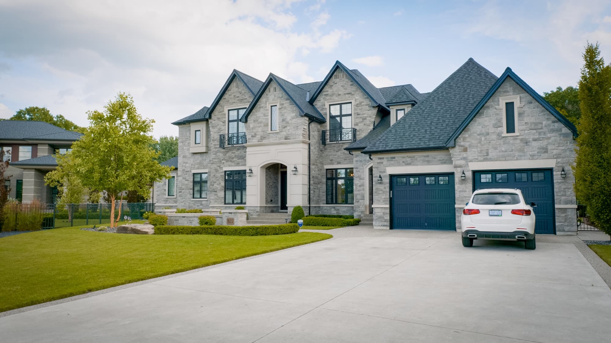 Custom-built stone exterior home with manicured lawn by Timberland Homes in Tecumseh, Ontario.